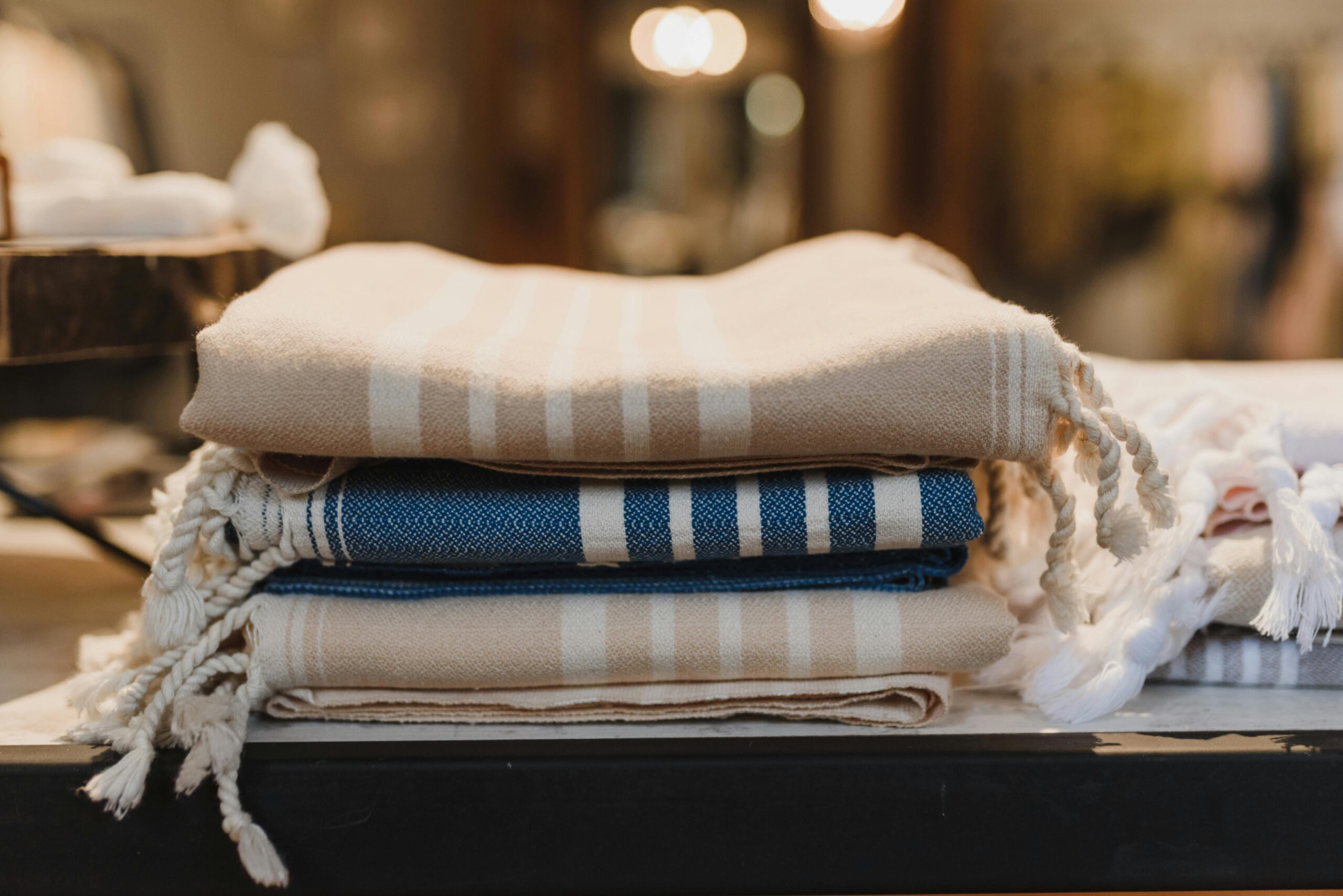 A neatly folded stack of beige and blue striped textiles on a table, creating a cozy, minimalist vibe.